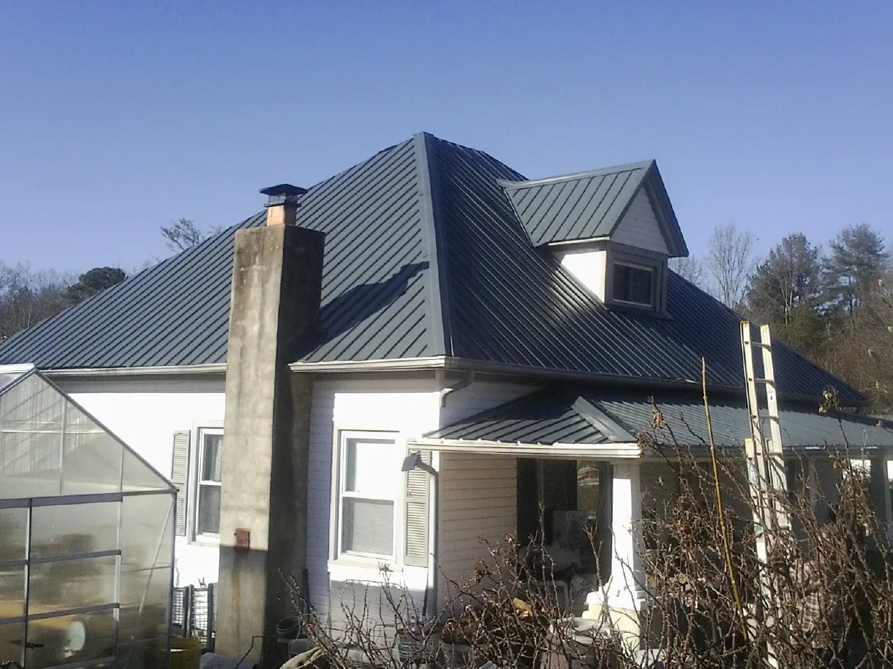 Dark blue standing seam metal roof on a white farmhouse with dormer — Slate & Tile Roof Repair by Roofing Brothers in Sumerduck