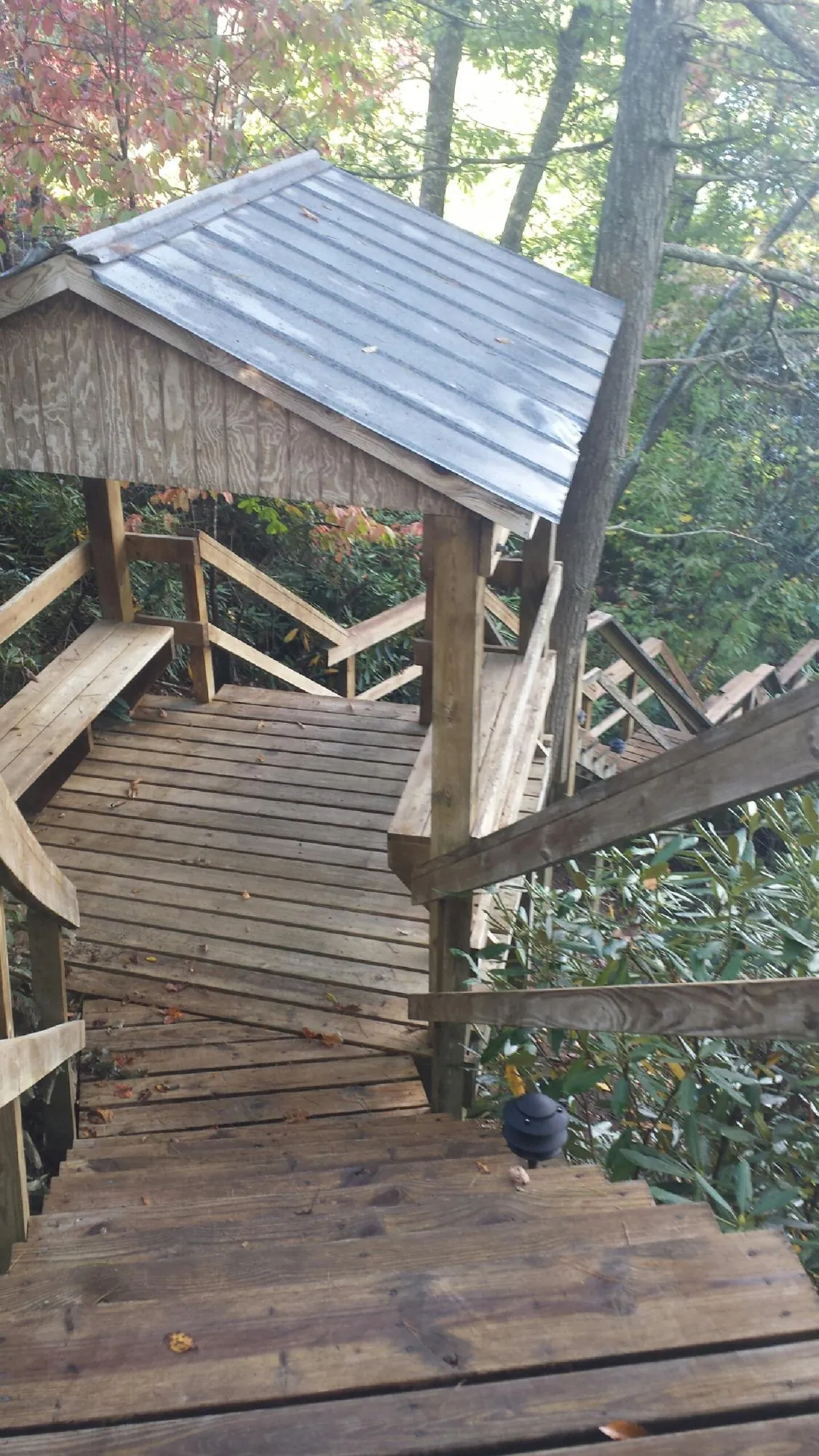 Metal roofed shelter over wooden steps on a wooded walkway — Skylight Repair & Installation work by our crew in Sumerduck
